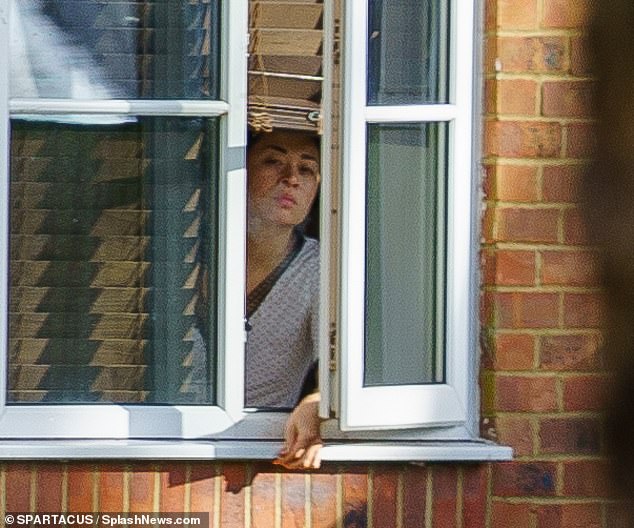 Casual: Katya went makeup free as she smoked by the window and was dressed casually in a white top while she appeared to have her brunette locks tied up