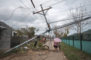 Residents pass by electrical posts toppled by Typhoon Goni in Malilipot, Philippines