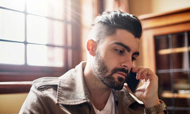 Shot of a handsome young man talking on a cellphone at home