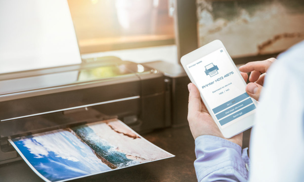 A wireless printer, with someone printing an image wirelessly from their smartphone